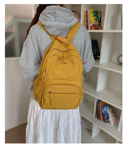 Detail eines senfgelben Rucksacks mit funktionellen Reißverschlüssen und Seitentaschen