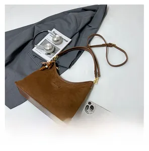 Detail of a brown matte suede crescent bag with retro beaded charm and zip closure