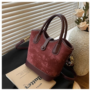 Détails du sac seau bordeaux avec panneaux texturés et pièces métalliques dorées