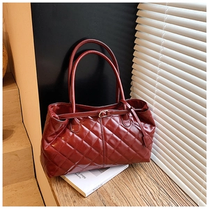 Gros plan du sac cabas matelassé rouge avec boucles en métal et texture cuir brillant