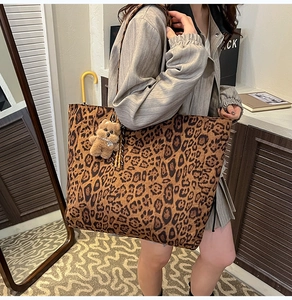 Detail of leopard print tote bag with brown plush bear charm and suede texture