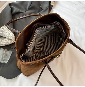 Detail view of large brown suede tote bag showing striped lining and inner pocket