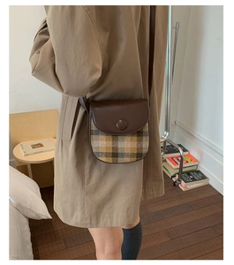 Detail of vintage plaid and brown leather saddle bag with adjustable shoulder strap