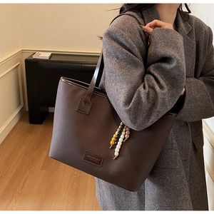 Détail du sac cabas marron foncé avec texture croisée et breloque en perles colorées