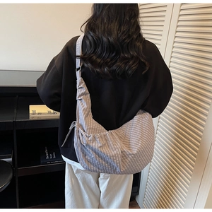 Plaid canvas hobo bag with drawstring details and wide shoulder strap shown on model