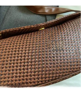 Macro shot of brown woven synthetic leather texture with a gold circular metal buckle
