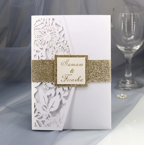 Detail of laser-cut floral pattern and gold glitter belly band on white wedding invitation