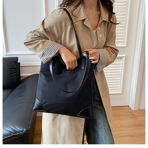 Close-up of black nylon tote bag with leather corner reinforcement shown on model