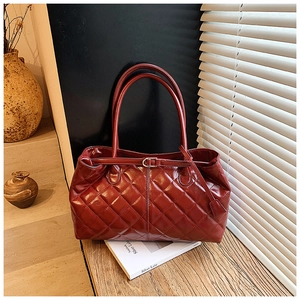 Détail du cabas en cuir matelassé bordeaux avec pompon et boucle de ceinture élégante