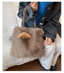 Detail of taupe faux fur tote bag featuring a woven handle and croissant plush pendant