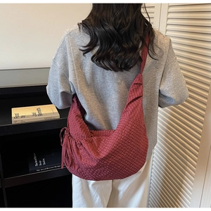 Detail of red and black checkered canvas dumpling bag with drawstring side and wide strap