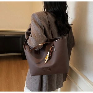 Détail d'un sac cabas en cuir mat marron foncé avec un élégant pendentif en perles