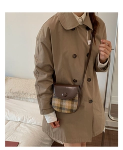 Detailed view of women's vintage plaid saddle bag worn with a classic khaki trench coat