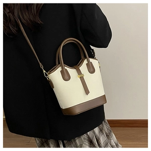 Vue arrière du sac seau bicolore rétro en tissu crème avec des détails en cuir marron