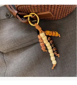 Detail of a brown woven texture handbag with golden ring buckle and colorful wooden beads