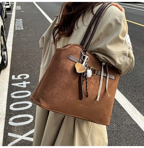 Detailed macro view of brown suede tote bag with sports charms and leather straps