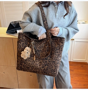 Detail of leopard print tote bag with plush bear pendant and woven tassel accessory