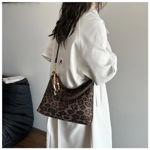 Details einer Leopard-Tasche mit Holzperlenanhängern und dunkelbraunen Trägern