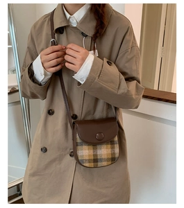Crossbody saddle bag in brown checkered fabric worn with a beige trench coat