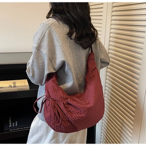 Detail of red checkered canvas hobo bag with adjustable strap in a casual lifestyle setting