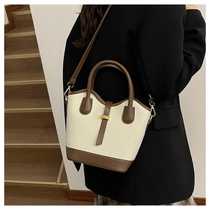 Détail du sac seau rétro en tissu crème avec finitions en cuir marron foncé