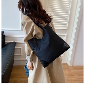 Detail of black tote bag with reinforced leather corners and durable wide shoulder strap