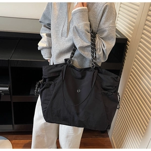Dettaglio della borsa tote in nylon nero con chiusura a coulisse e spalline a righe