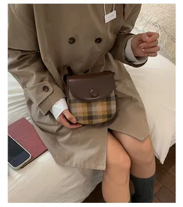 Close-up of retro brown plaid saddle bag styled with a khaki trench coat for autumn