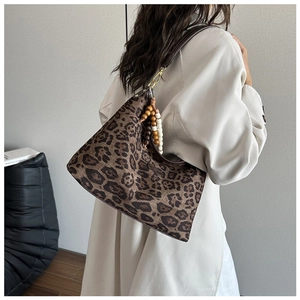 Detail of leopard print hobo bag with dark brown leather strap and wooden bead tassel