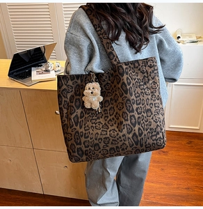 Detailed side view of leopard print tote bag with a cute plush bear charm on its strap