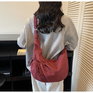 Detailed view of red checkered canvas dumpling bag worn by model showing its large capacity
