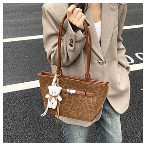 Detail view of brown leopard print tote bag with faux suede texture and plush bear charm