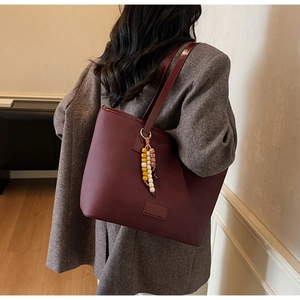 Détail d'un sac cabas bordeaux avec texture cuir mat et breloque en perles colorées