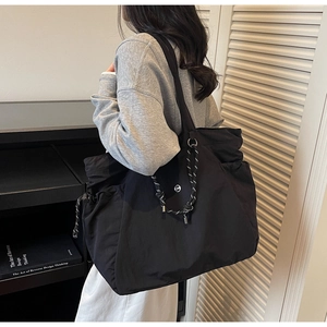 Dettaglio della grande borsa tote in nylon nero con logo bianco tondo e coulisse tessuta