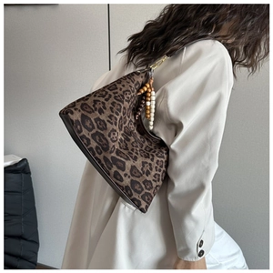 Detail der Hobo-Tasche mit Leopardenmuster und Perlen-Quasten-Anhänger am Schultergurt