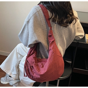 Detail of red checkered canvas dumpling bag with adjustable shoulder strap and drawstring