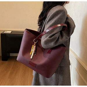 Gros plan d'un cabas bordeaux avec perles ethniques sur un blazer en laine chevron