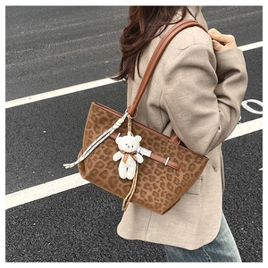 Brown leopard print tote bag with plush bear charm and leather strap detail