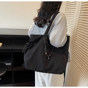 Dettaglio della borsa tote nera minimalista con coulisse intrecciata e hardware in metallo