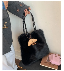 Detail of black fuzzy tote bag with braided leather handles and a cute croissant charm