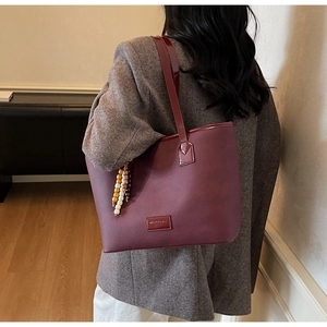 Détail du sac cabas bordeaux en similicuir avec pompon perlé et bandoulière fine