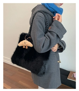 Detail of black faux fur tote with woven handle and yellow croissant plush charm