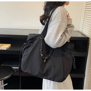 Dettaglio della grande borsa tote in nylon nero con coulisse e anello di metallo