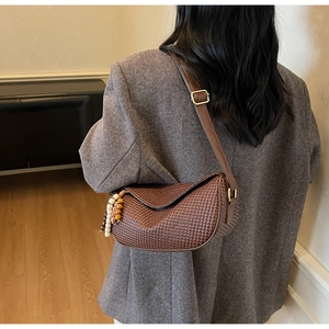 Detail of dark brown woven texture shoulder bag with decorative wooden beads and metal buckle