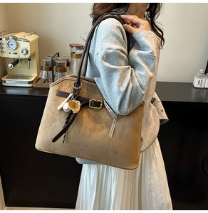 Detail of brown suede tote bag with leather straps and decorative gold metal buckle