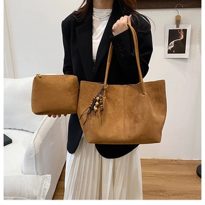 Detail of brown suede tote bag featuring beaded charm and matching zipper pouch