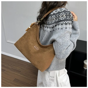 Detail of dark brown suede hobo bag featuring retro wooden beads and metal hardware
