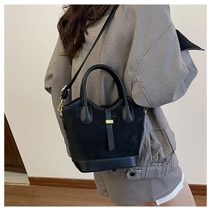 Vue latérale d'un sac seau noir en daim avec boucle dorée porté par un mannequin
