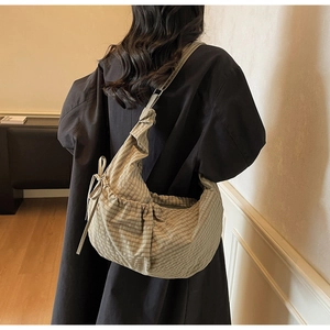 Detail of checkered canvas bag with adjustable strap and stylish drawstring folds