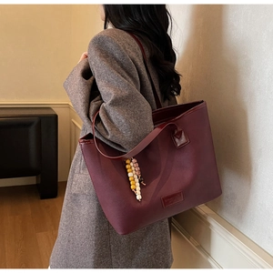 Détail du cabas en cuir PU bordeaux avec texture vintage et pendentif en perles
